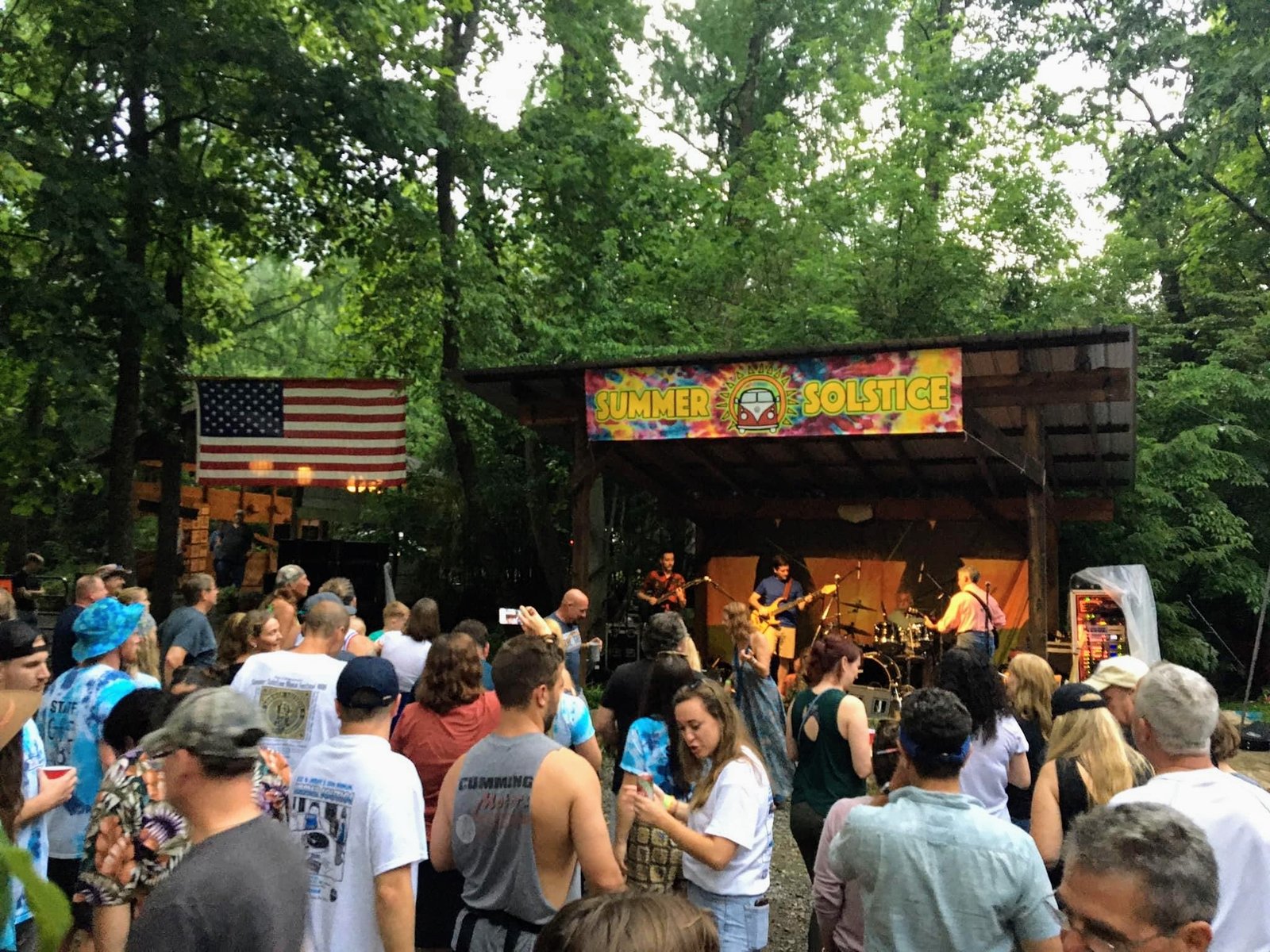 A Solstice crowd enjoying live music beneath the trees